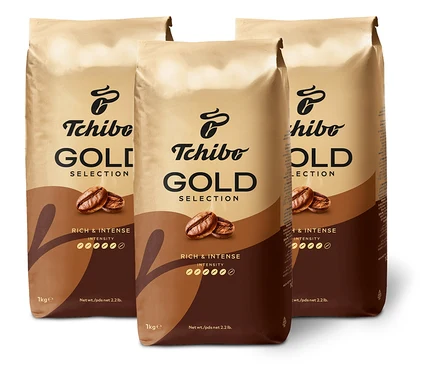 Tri balenia kávy Tchibo Gold Selection stoja na bielom pozadí.