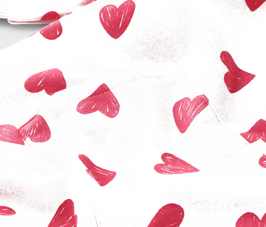 Detailný záber na bielu látku s červeným vzorom srdca.