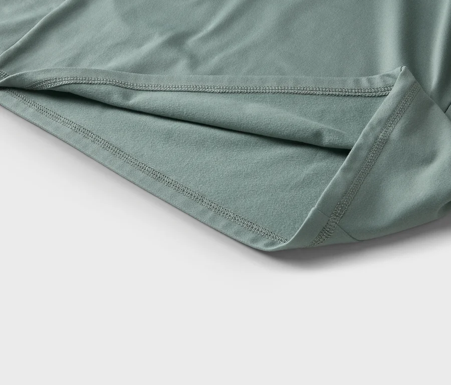 Detailný záber mätovo zeleného materiálu s viditeľnými švami a záhybmi.
