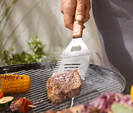 Muž griluje steak pomocou multifunkčného nástroja na grilovanie.
