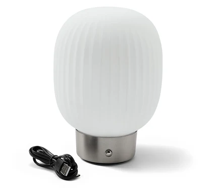 LED akumulátorová stolná lampa so skleneným tienidlom stojí vedľa čierneho nabíjacieho kábla.