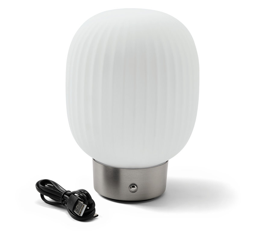 LED akumulátorová stolná lampa so skleneným tienidlom stojí vedľa čierneho nabíjacieho kábla.