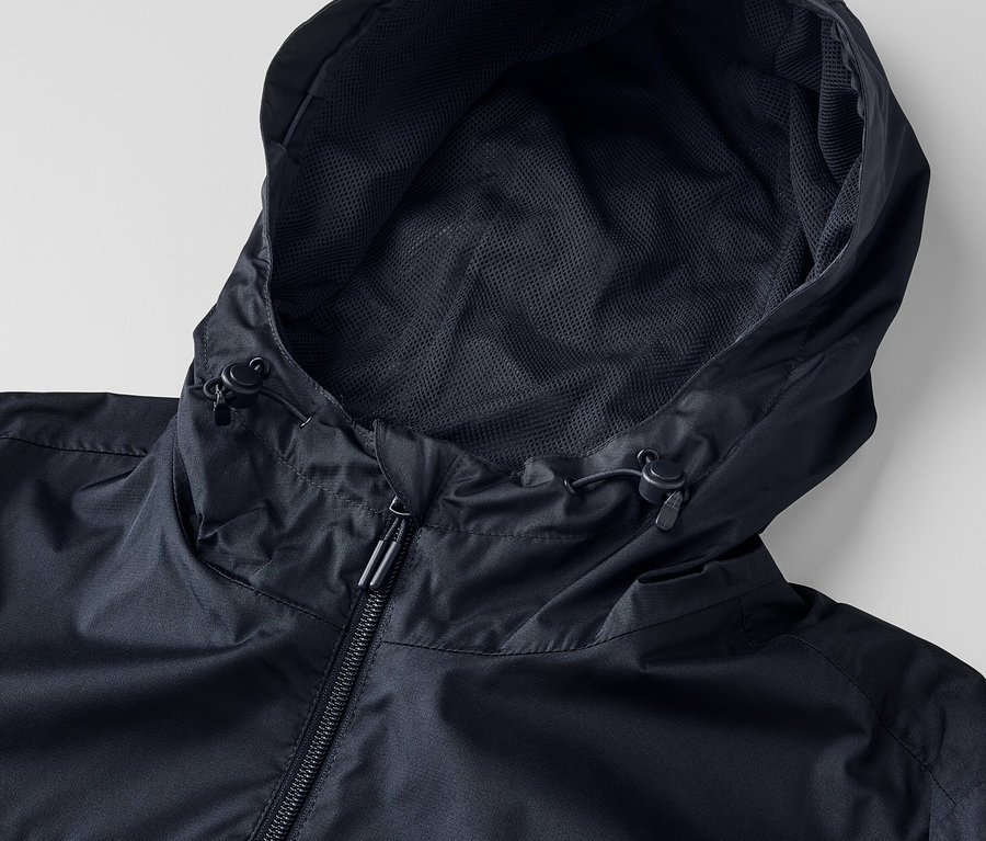 Detail čiernej unisex bundy do dažďa s kapucňou a zipsom.