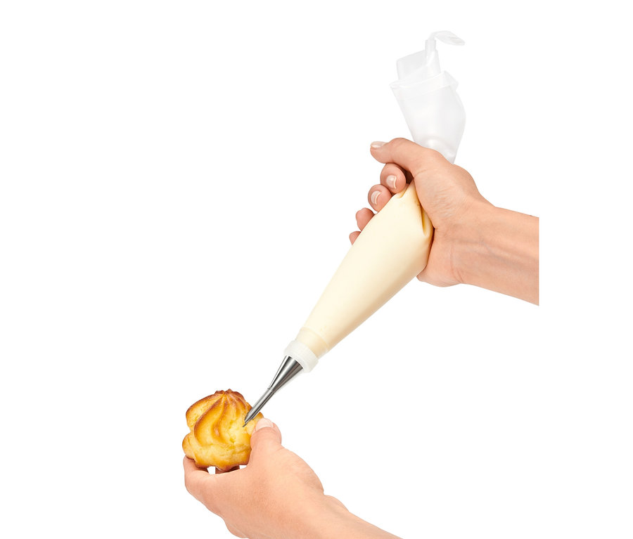 Ruka plní profiterolku krémom pomocou súpravy zdobiacich špičiek.