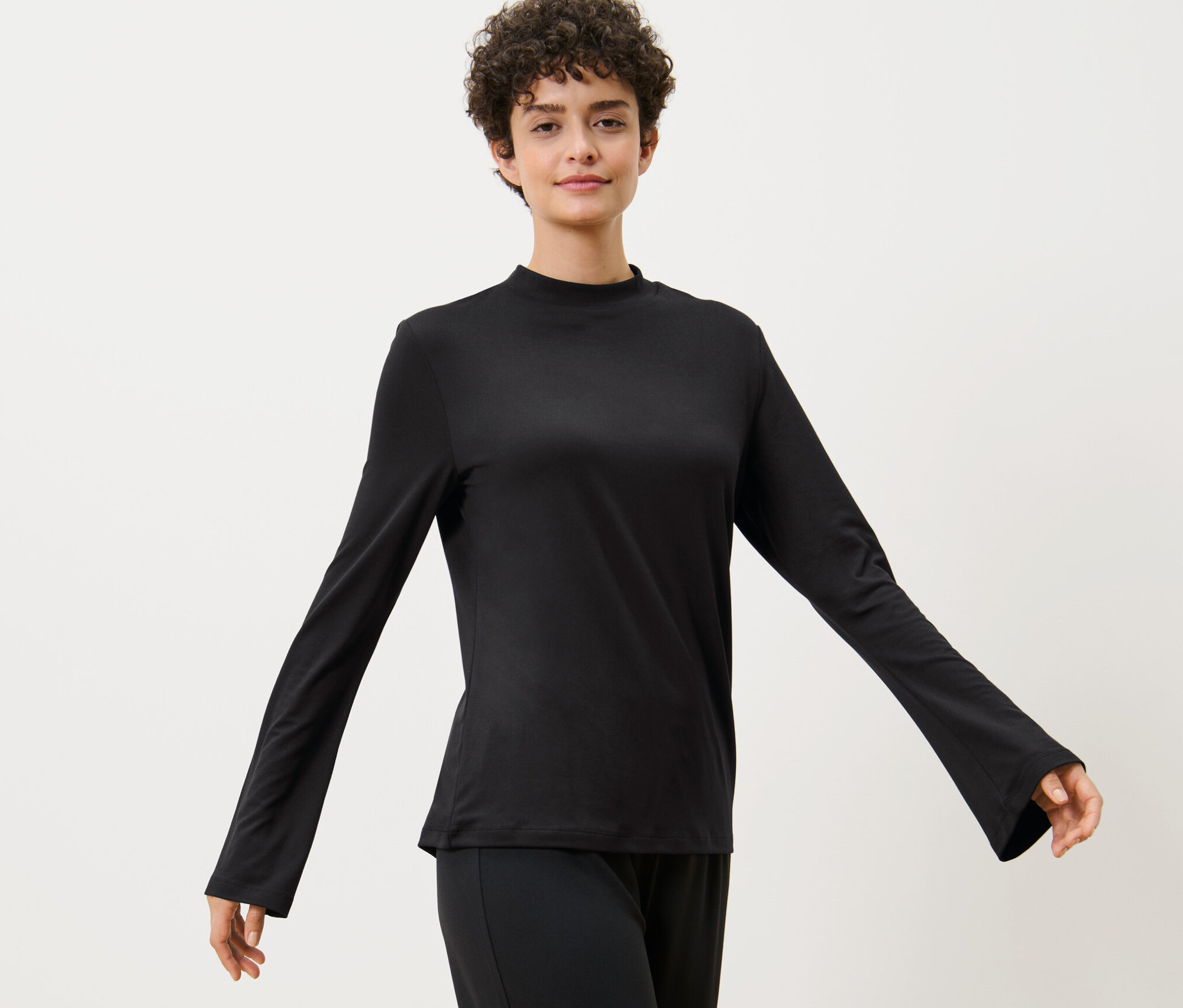 Žena pózuje v športovom tričku s dlhým rukávom.