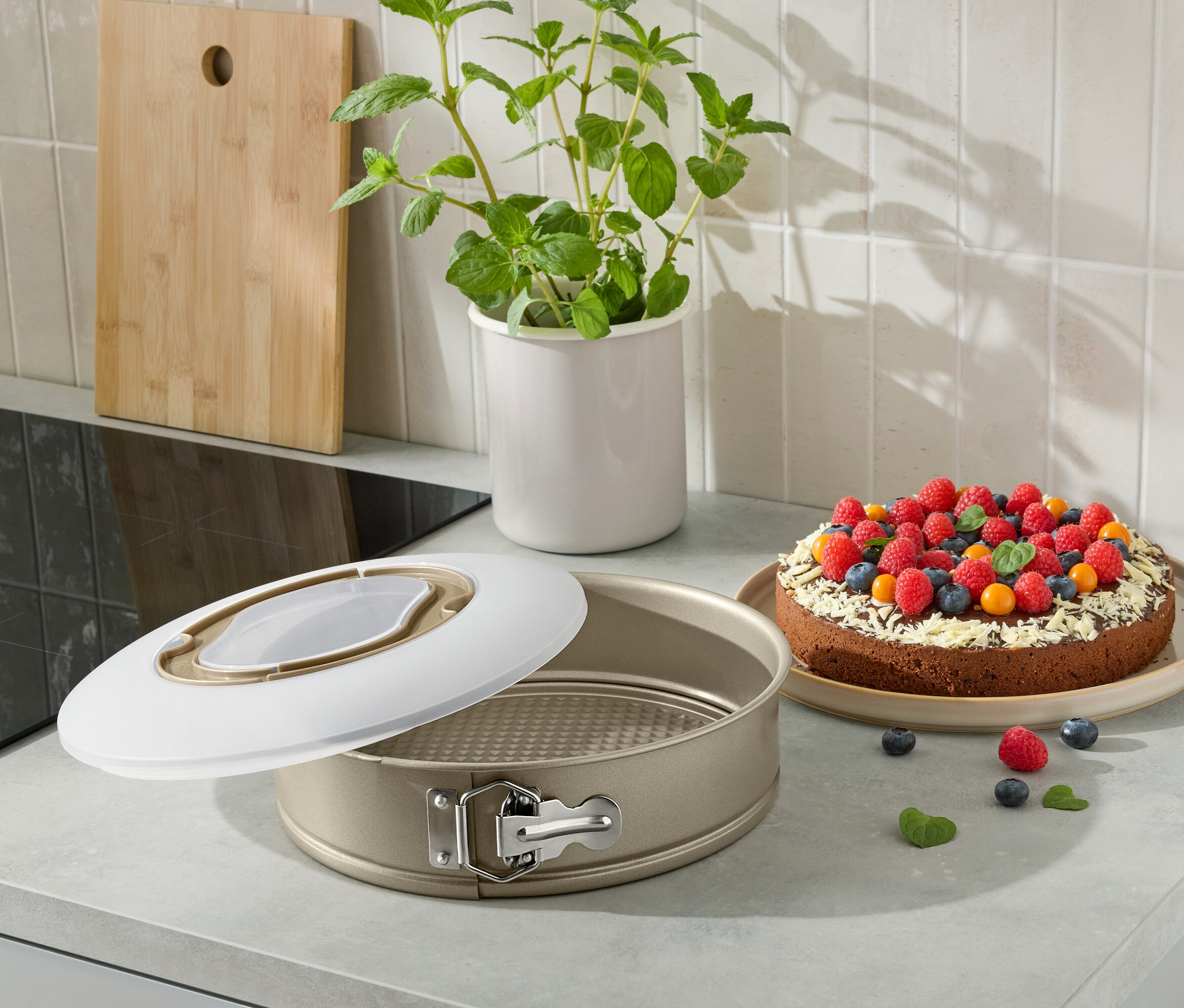 Otvorená forma na tortu s upečenou tortou zdobenou ovocím na kuchynskej linke.