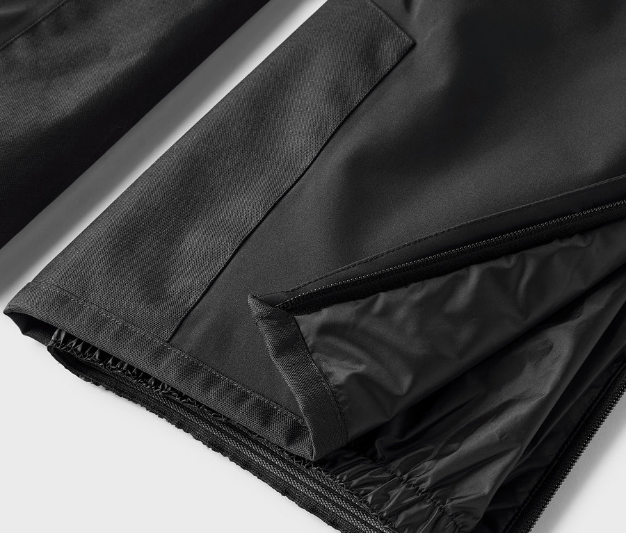 Detail čiernych nohavíc s rozopnutým zipsom.