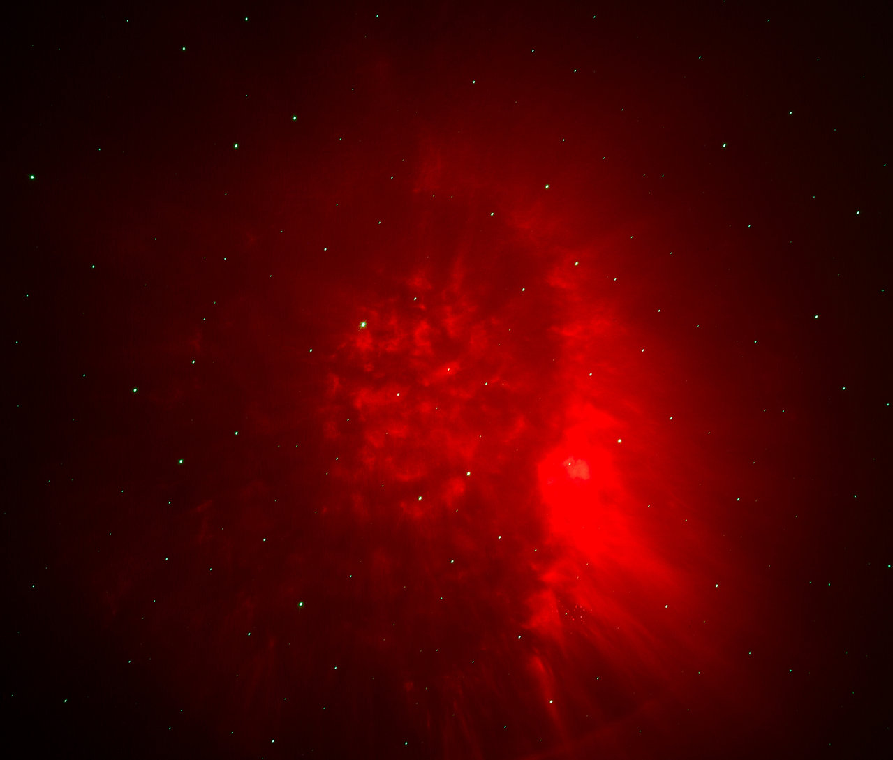 Červená hmlovina s hviezdami na tmavom pozadí.