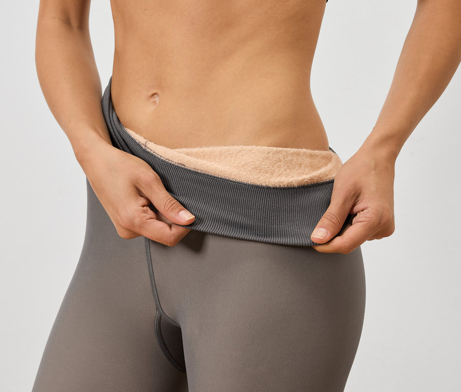 Žena drží sivé legíny s hrejivou podšívkou.