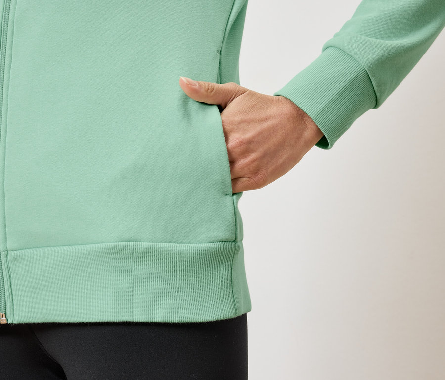 Detail svetlozelenej dámskej mikiny na zips s rukou vo vrecku.