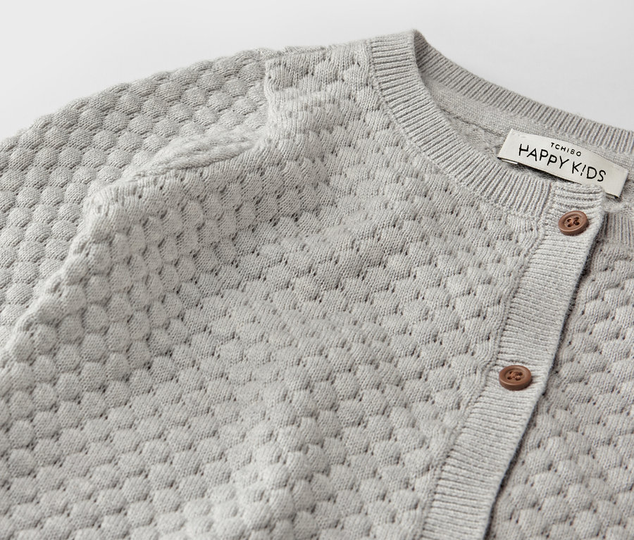 Detail sivého pleteného svetra pre bábätká.