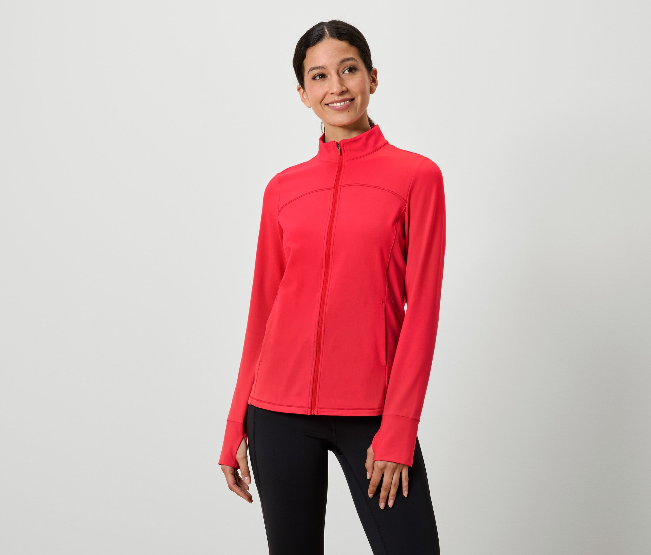 Žena má na sebe červenú bundu na zips a čierne legíny.