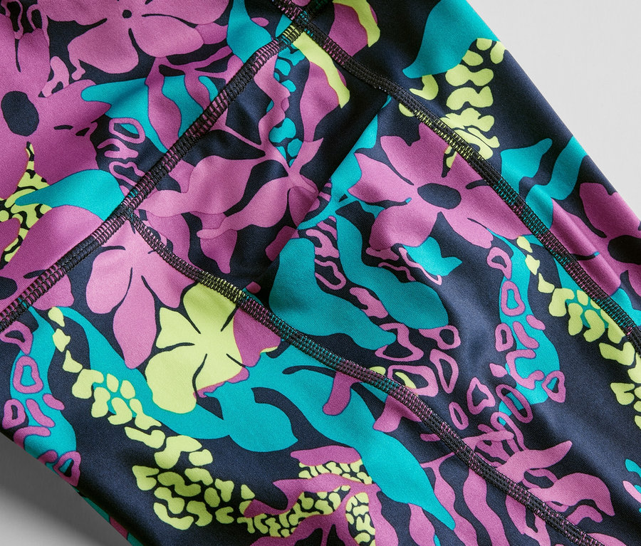 Detailný záber na 3/4 športové legínsy s celoplošnou potlačou kvetov a listov v ružovej, tyrkysovej a žltej farbe.