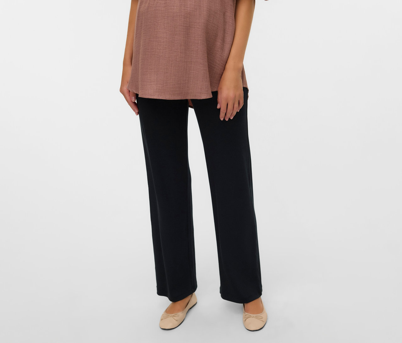 Žena má na sebe hnedý top a voľné legínsy MAMALICIOUS »MLEMILY« a béžové balerínky.