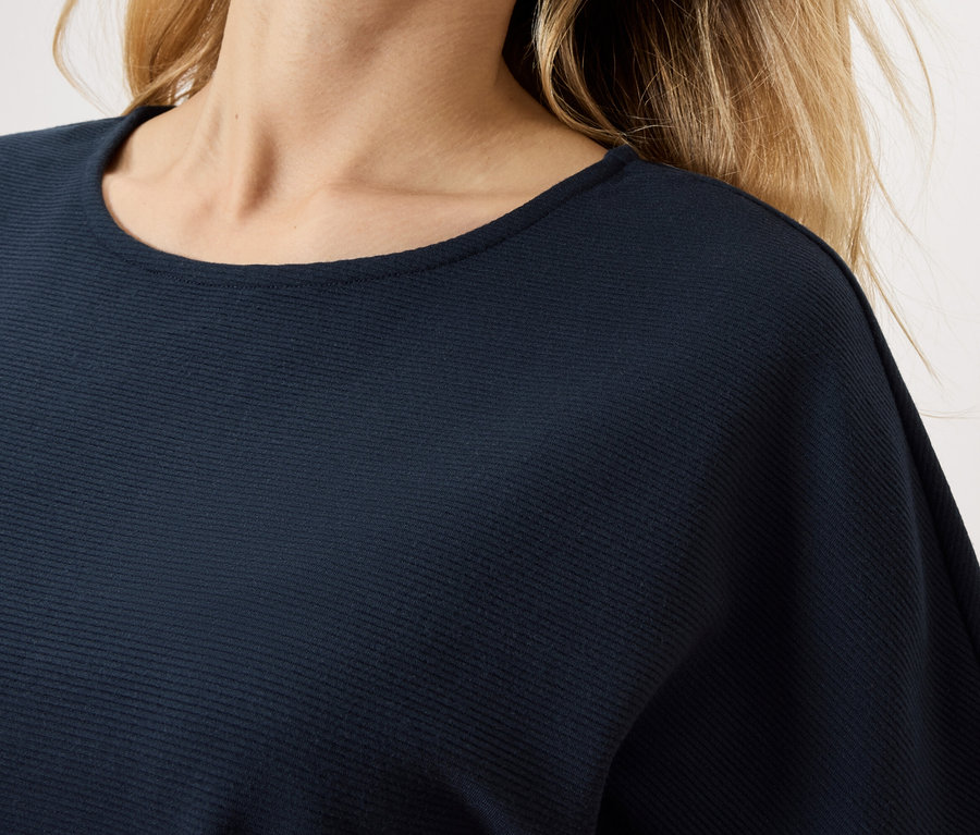 Detail ženy v tmavomodrom tope.