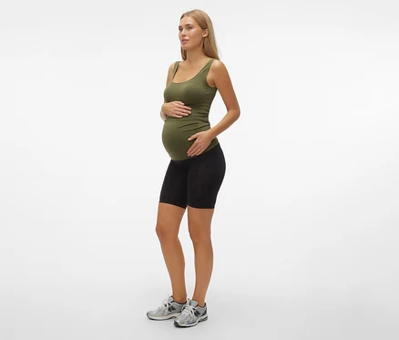 Tehotná žena v olivovom tielku a čiernych skinny šortkách MAMALICIOUS »MLTIA JEANNE«, mellow buff, stojí bokom.