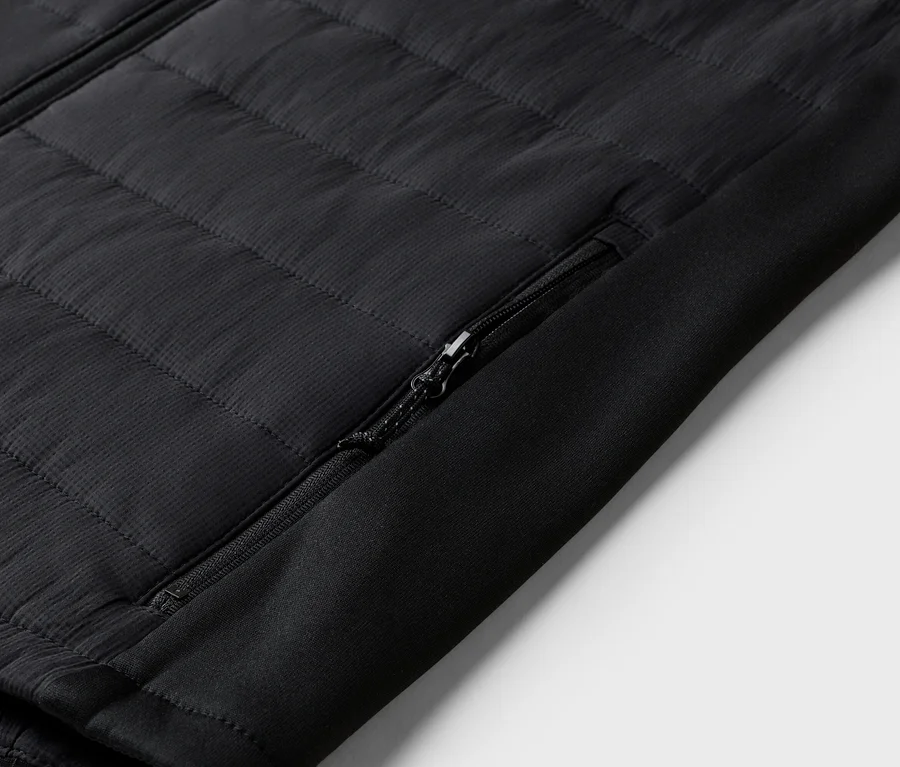 Detail čiernej prešívanej bundy s vreckom na zips na rukáve.