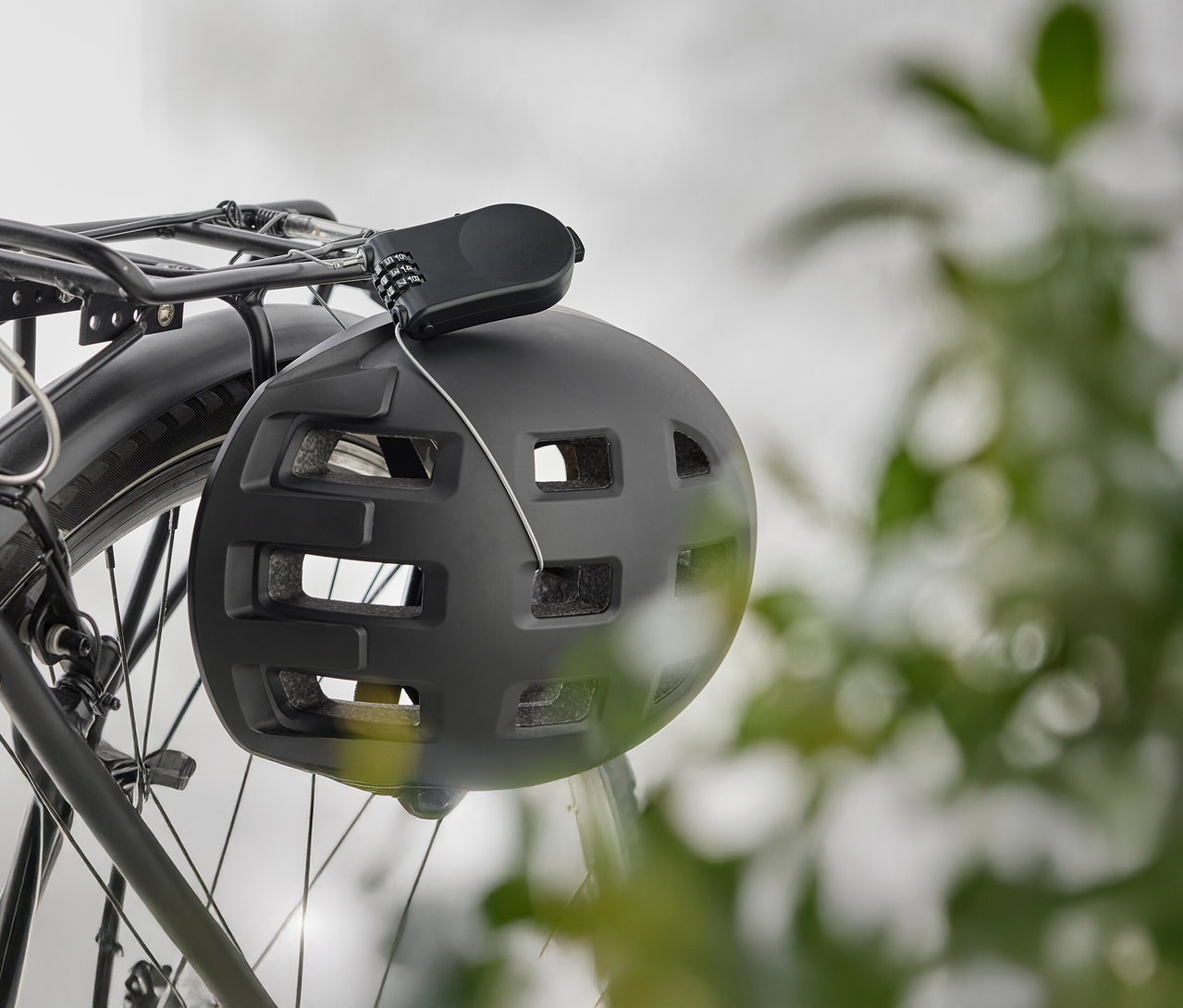 Čierna cyklistická prilba visí so zámkom na batožinovom nosiči bicykla.