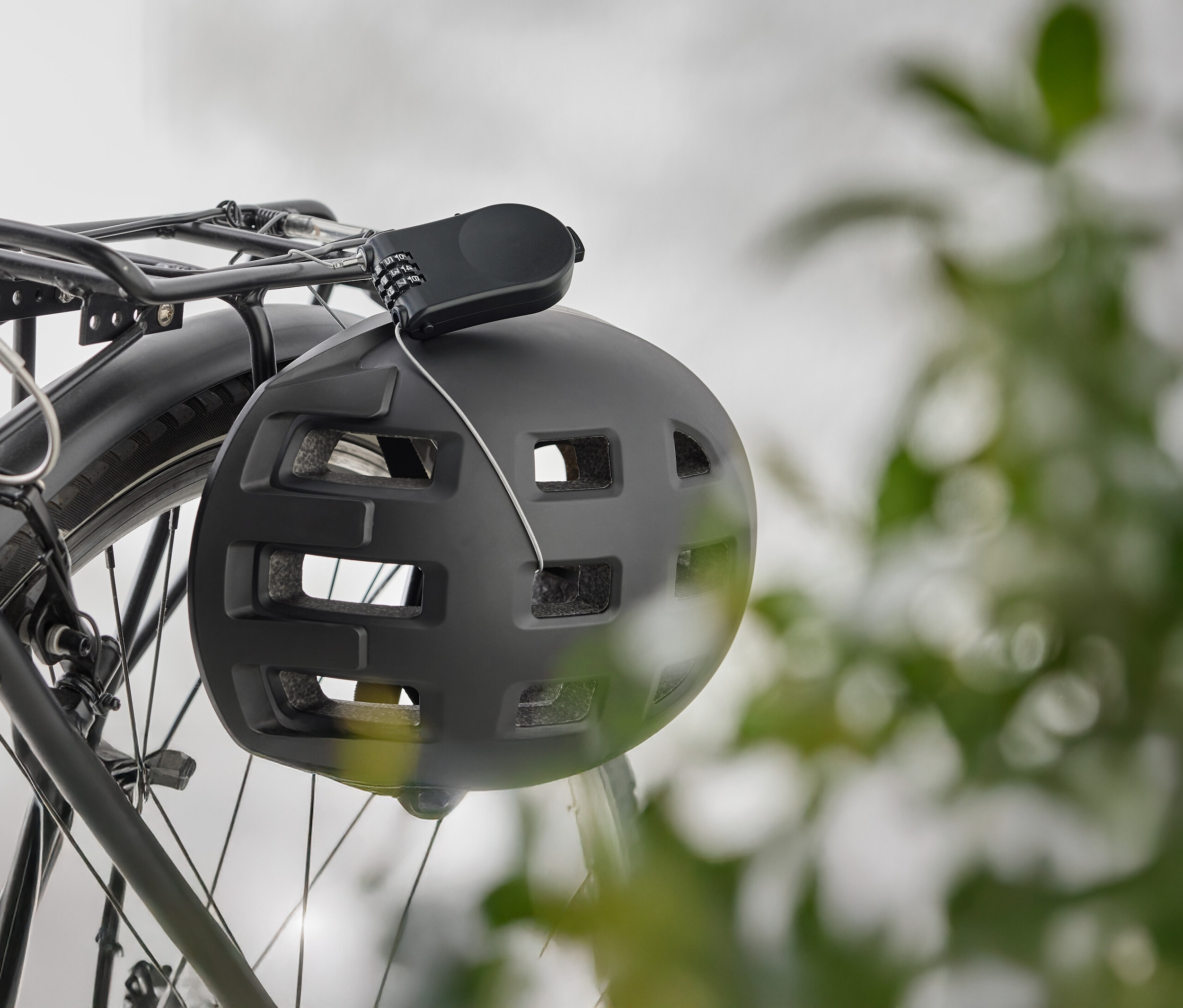 Čierna cyklistická prilba visí so zámkom na batožinovom nosiči bicykla.