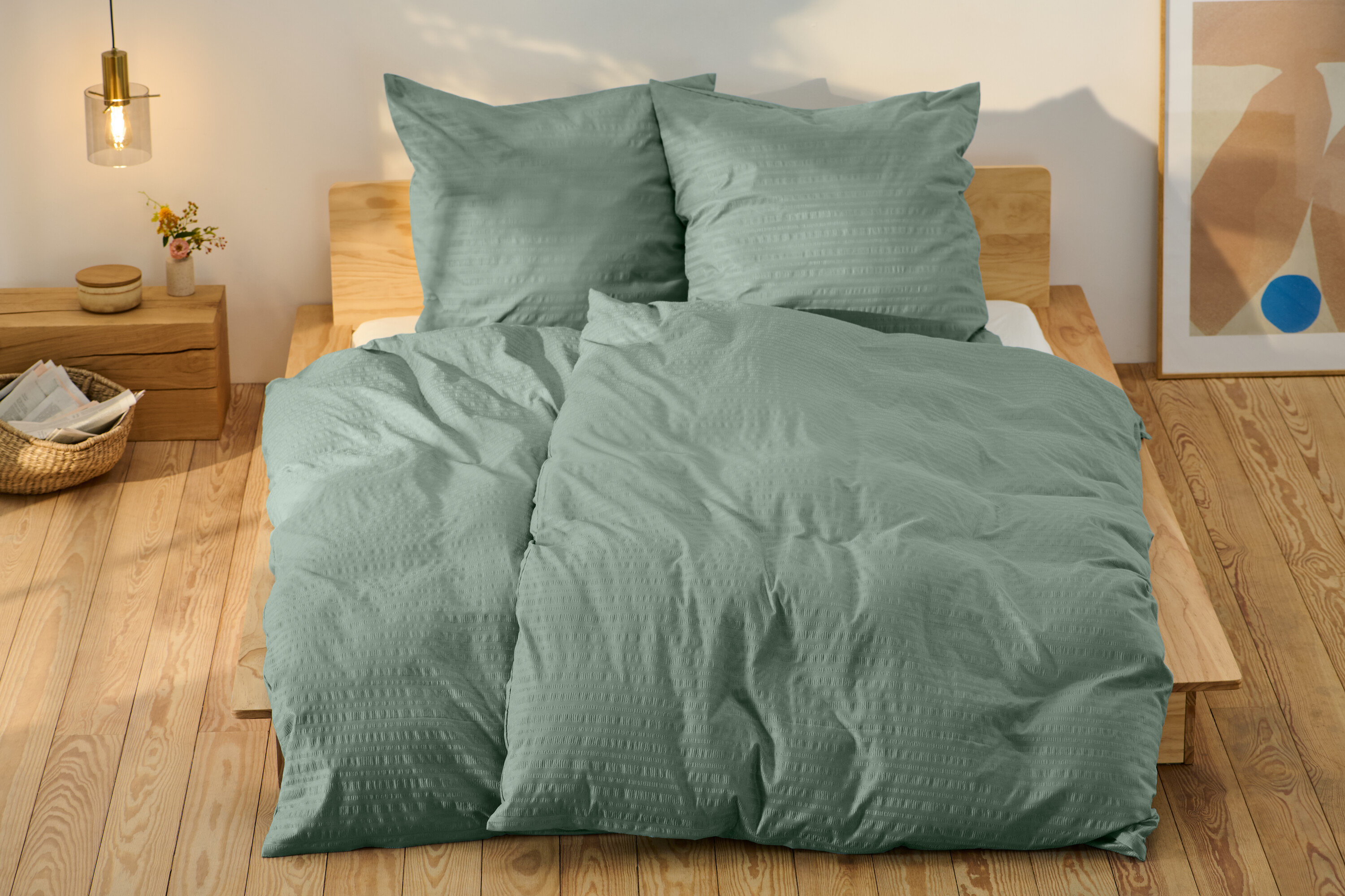 Zelená krepová posteľná bielizeň štandardnej veľkosti a jedna nadmernej veľkosti na posteli.