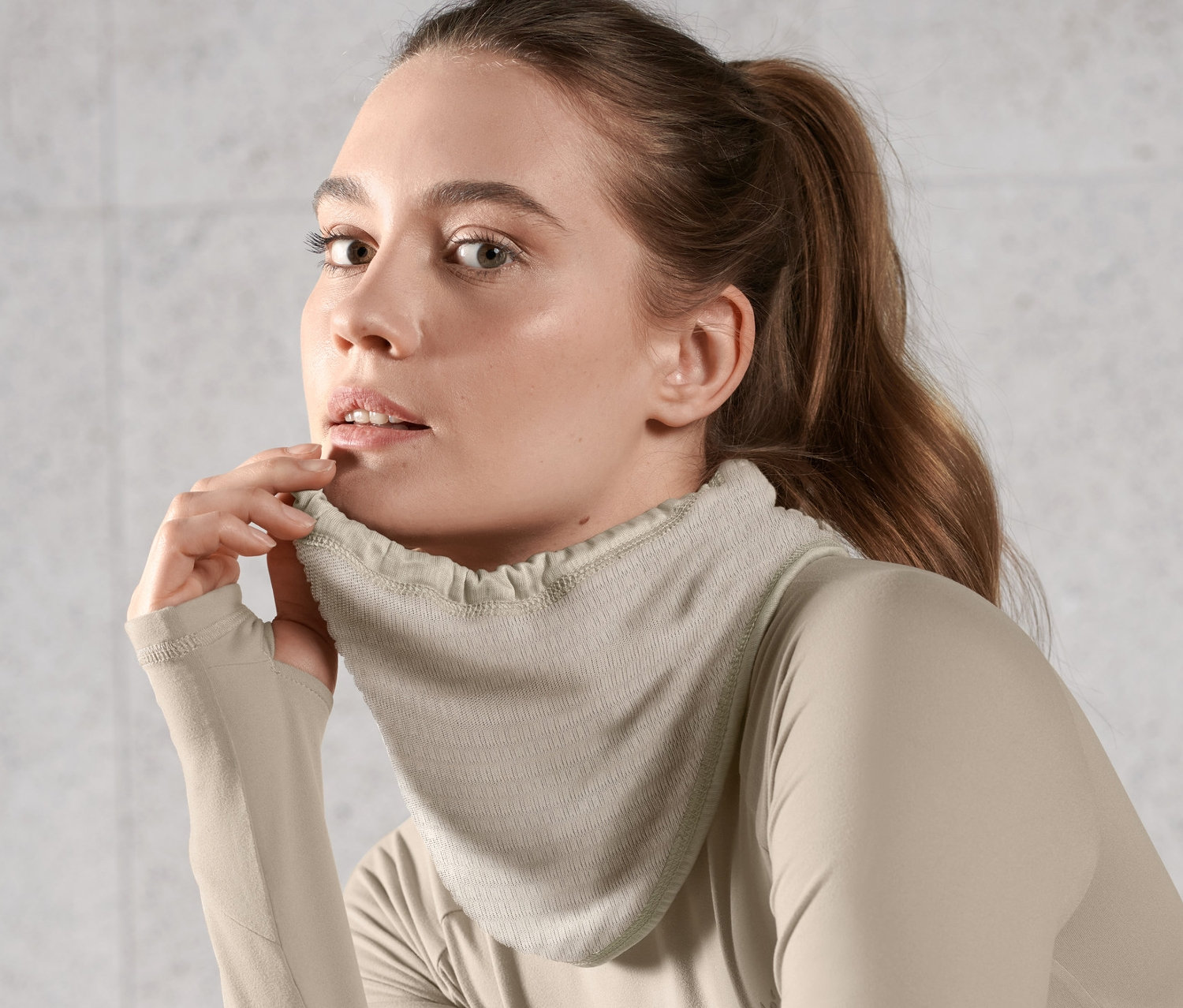 Žena nosí svetlohnedú multifunkčnú termo šatku a top s dlhým rukávom.