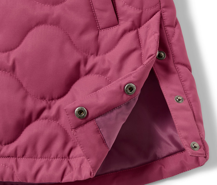 Detail detského prešívaného kabáta s patentkami.