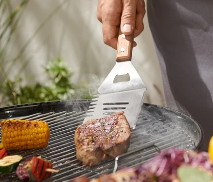 Muž griluje steak pomocou multifunkčného nástroja na grilovanie.
