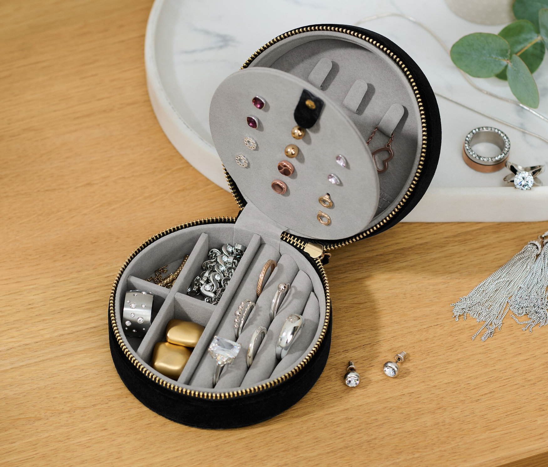 Čiastočne otvorená malá šperkovnica s rôznymi šperkami vo vnútri.