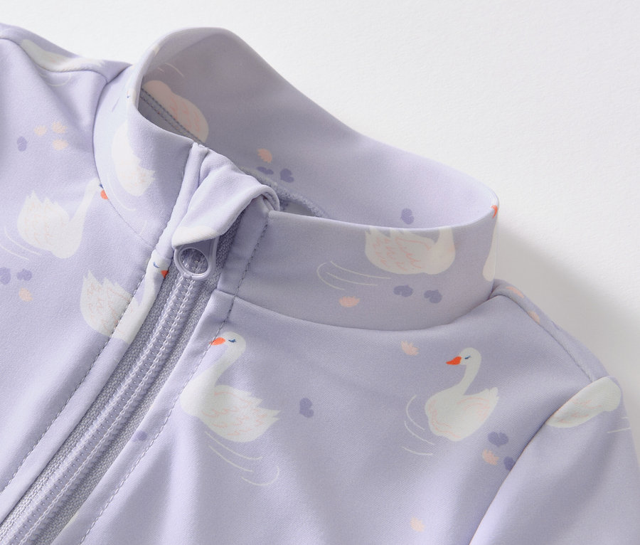 Detail fialového overalu so zipsom a potlačou labutí, s UV faktorom 80 pre bábätká.