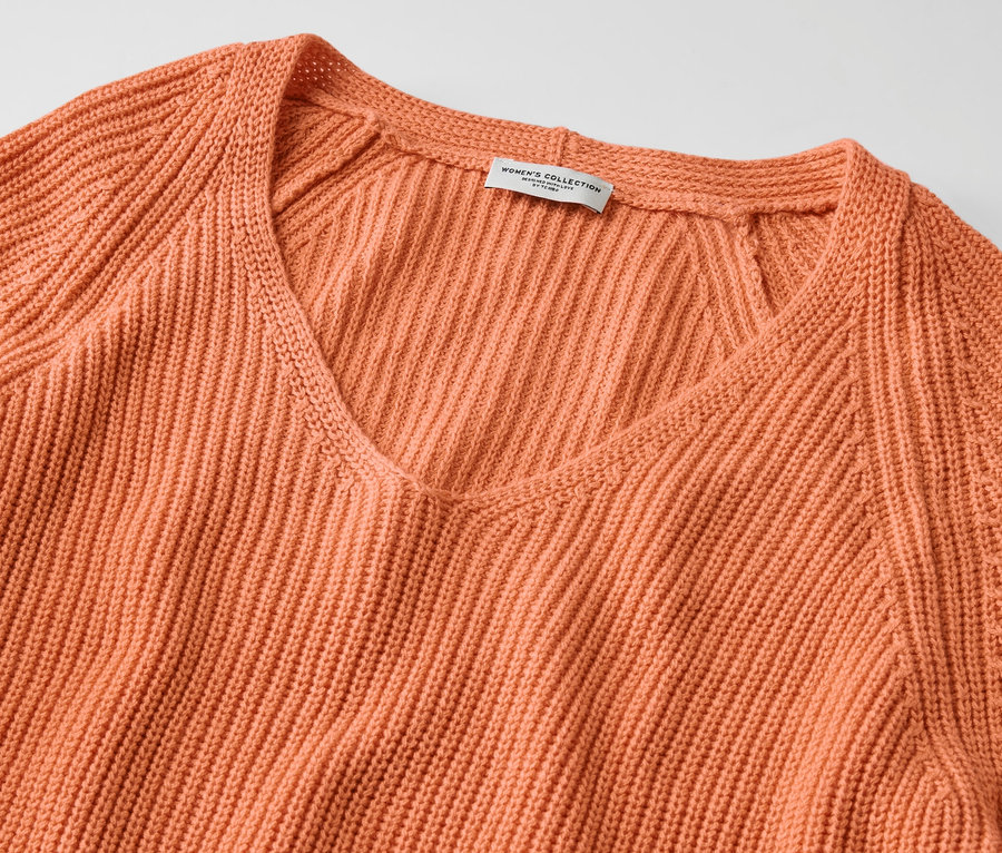 Detail broskyňového pleteného pulóvra s výstrihom do V.