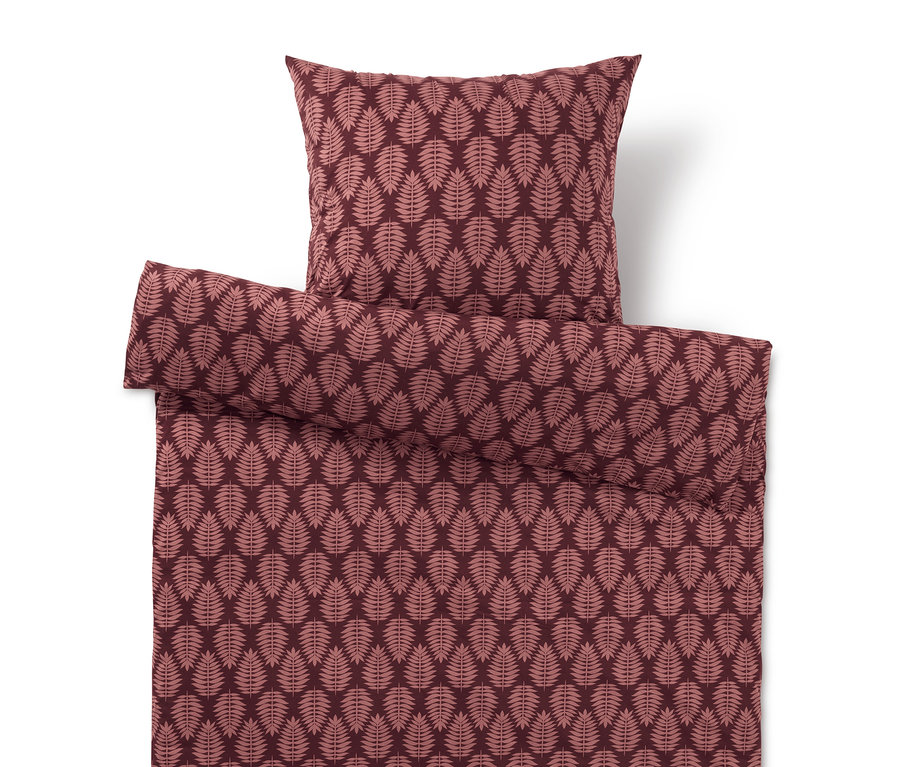 Obliečky a vankúš s listovým vzorom v odtieňoch červenej.