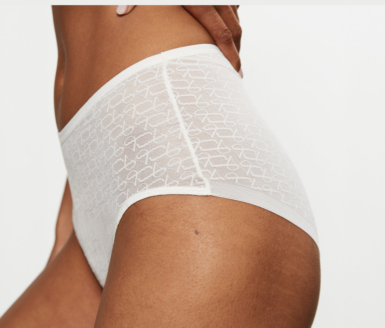 Detail osoby v krémovobielych, vysokých, priesvitných nohavičkách Triumph Signature Sheer Maxi EX so vzorom.