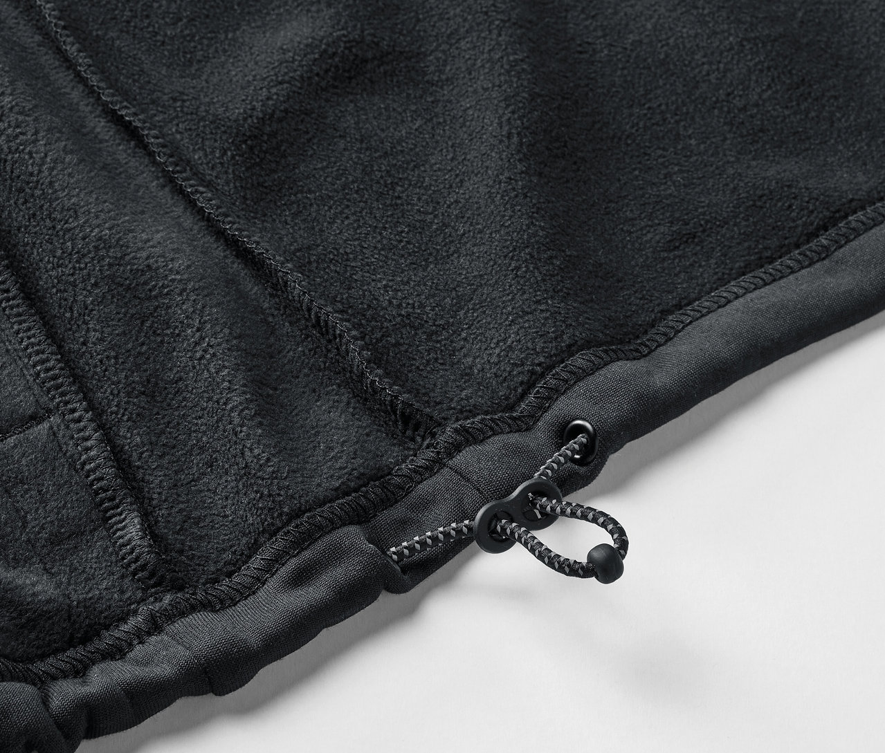Detail čierneho fleecového svetra so sťahovacou šnúrkou.
