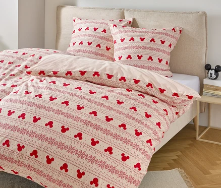 Posteľ s obliečkami s motívom Mickey Mouse a dvoma vankúšmi s podobným vzorom.