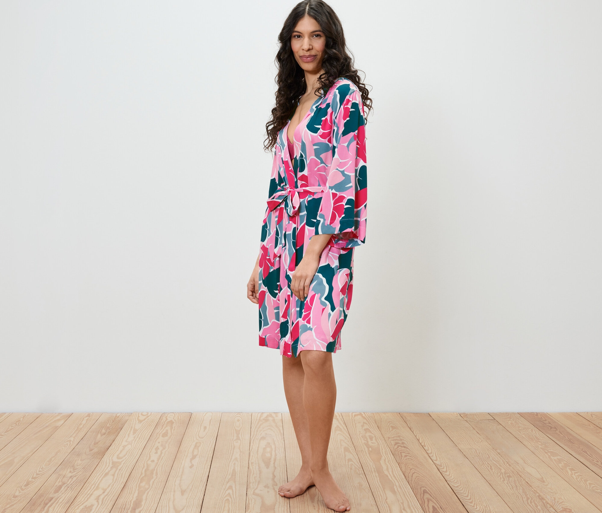 Žena stojí bokom a má na sebe župan s kvetinovým vzorom.