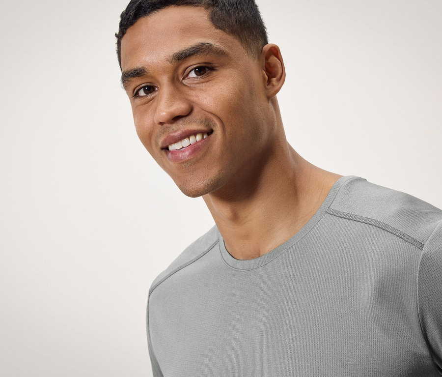 Portrét usmievajúceho sa muža v sivom tričku.