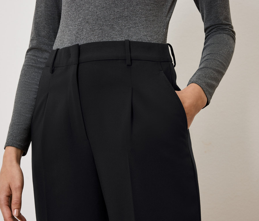 Žena má ruku vo vrecku čiernych nohavíc.