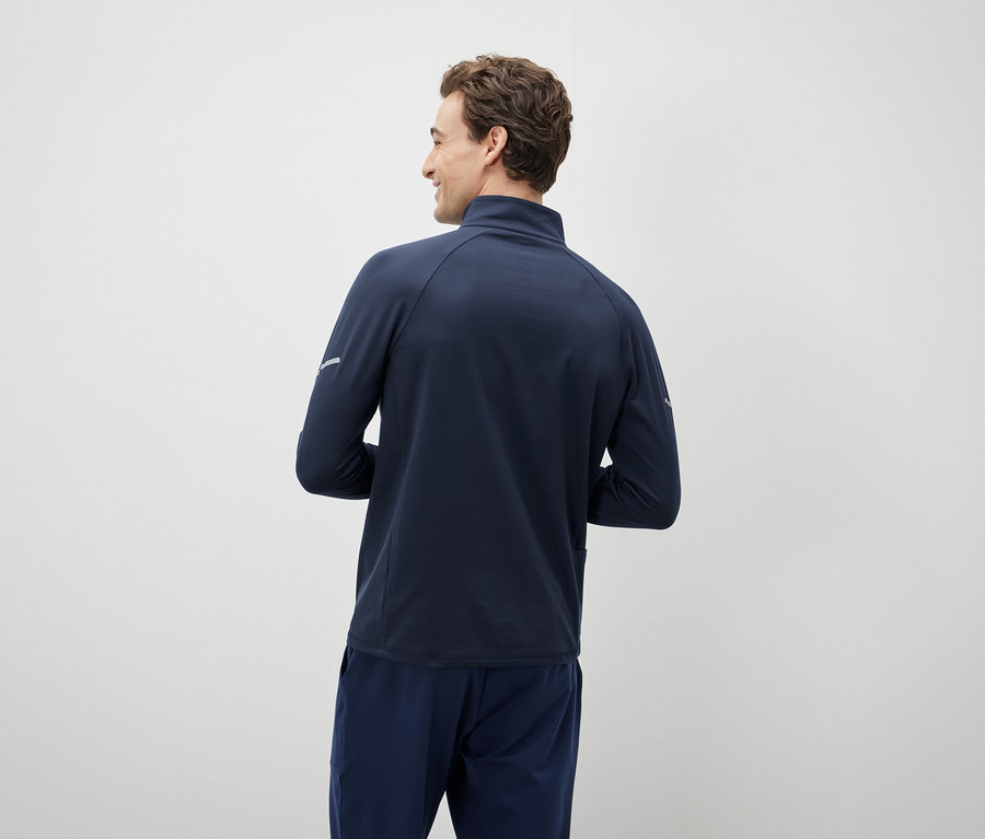 Muž sa pozerá cez plece a má na sebe tmavomodrú bundu a nohavice.