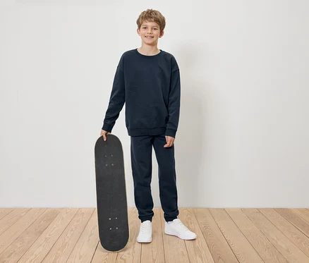 Chlapec v tmavomodrej súprave drží skateboard.
