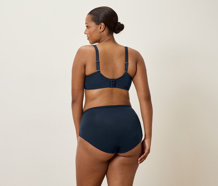 Žena s tmavými vlasmi, videná zozadu, má na sebe tmavomodrú podprsenku a zodpovedajúce nohavičky.