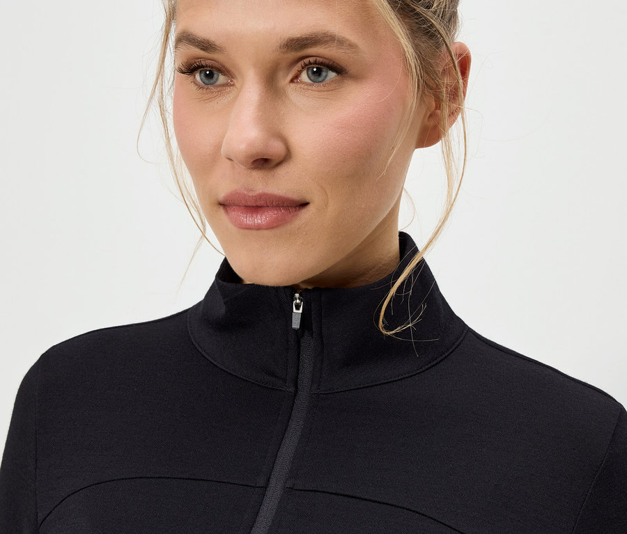 Detail ženy s blond vlasmi v čiernej bunde na zips.