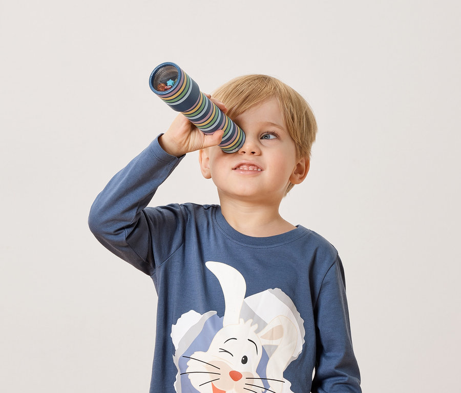 Blond chlapec sa pozerá cez kaleidoskop.