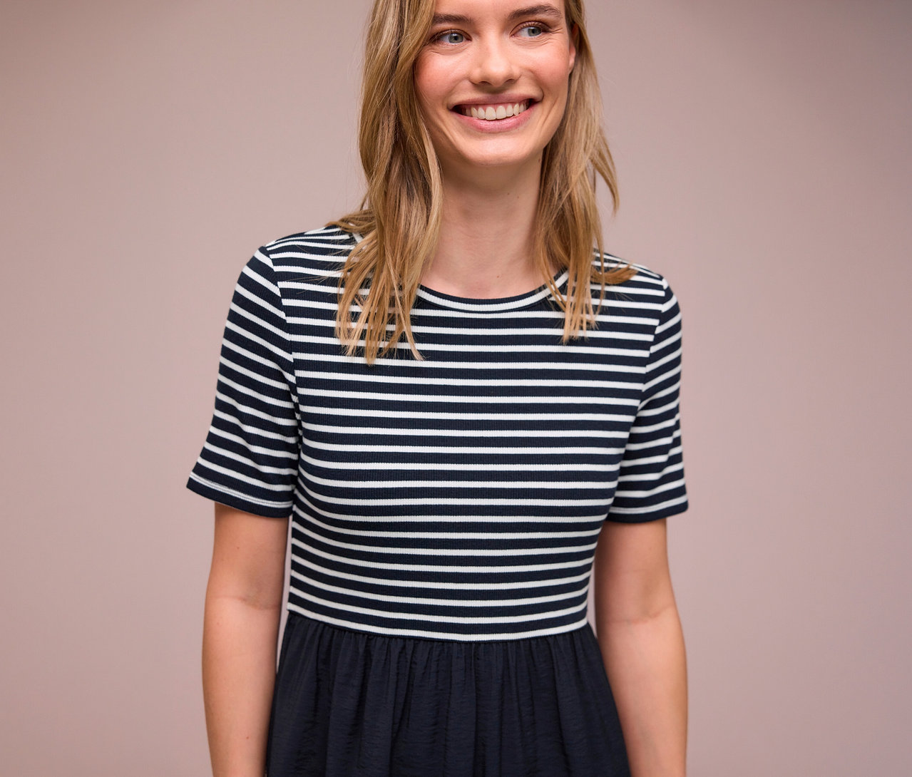 Usmievavá žena má na sebe šaty Street One s modro-bielymi pruhmi.