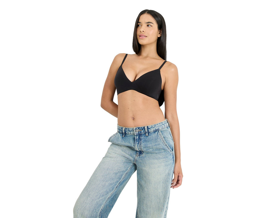 Žena má na sebe čiernu podprsenku a modré džínsy.