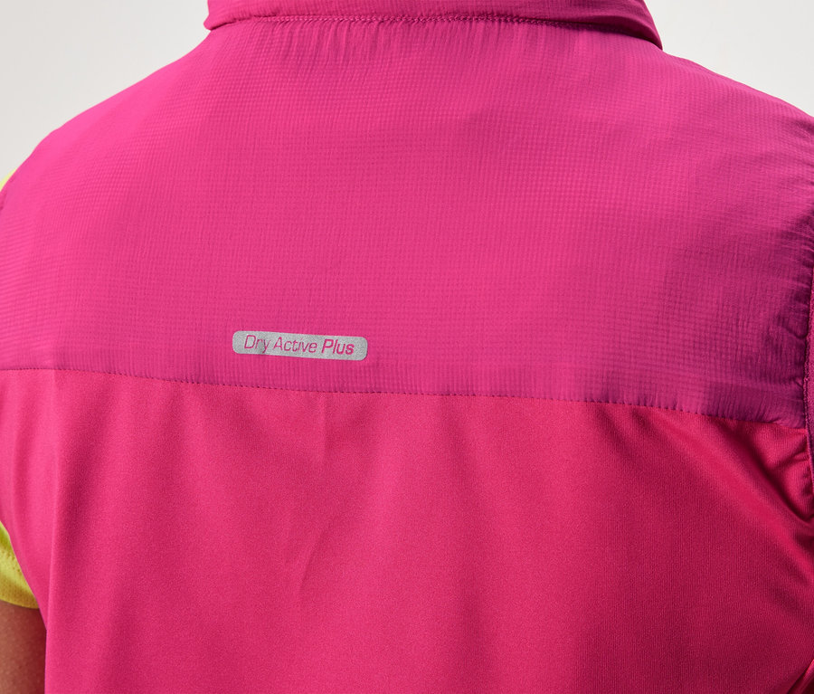 Pohľad zozadu na osobu v ružovej veste s nápisom "Dry Active Plus" na svetlozelenom tričku.