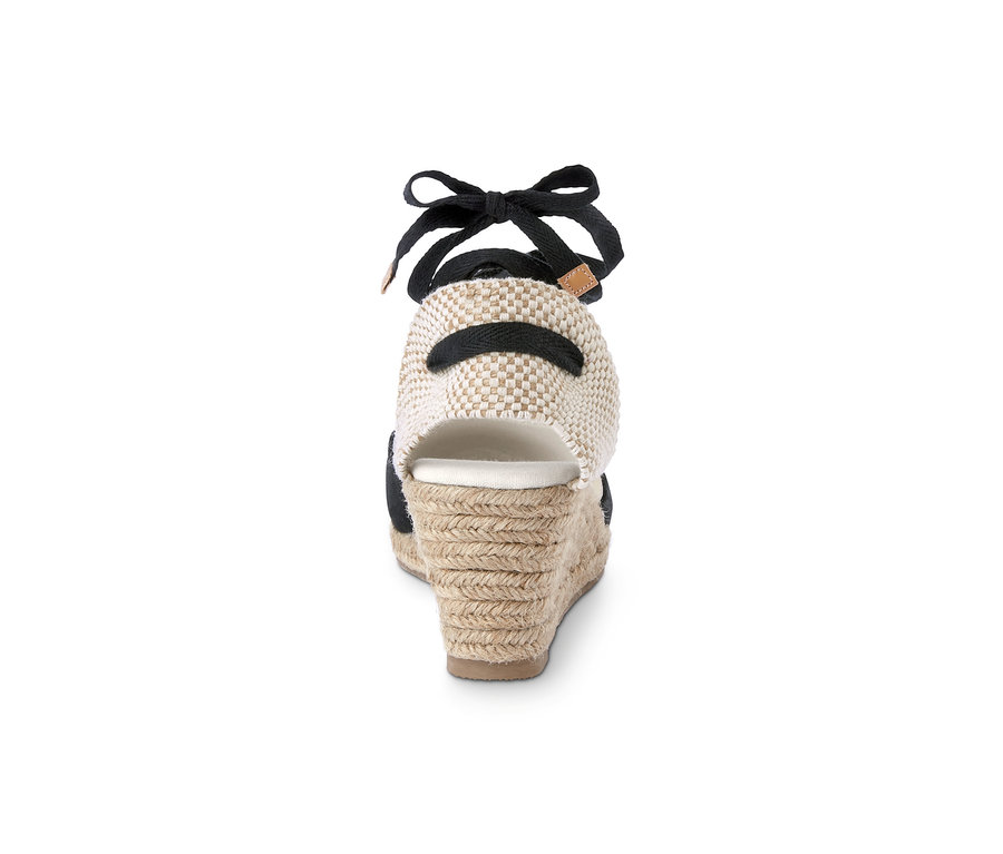 Detail zadnej strany espadrilky s klinovým podpätkom, ktorá má čiernu stuhu a béžovú pletenú pätu.