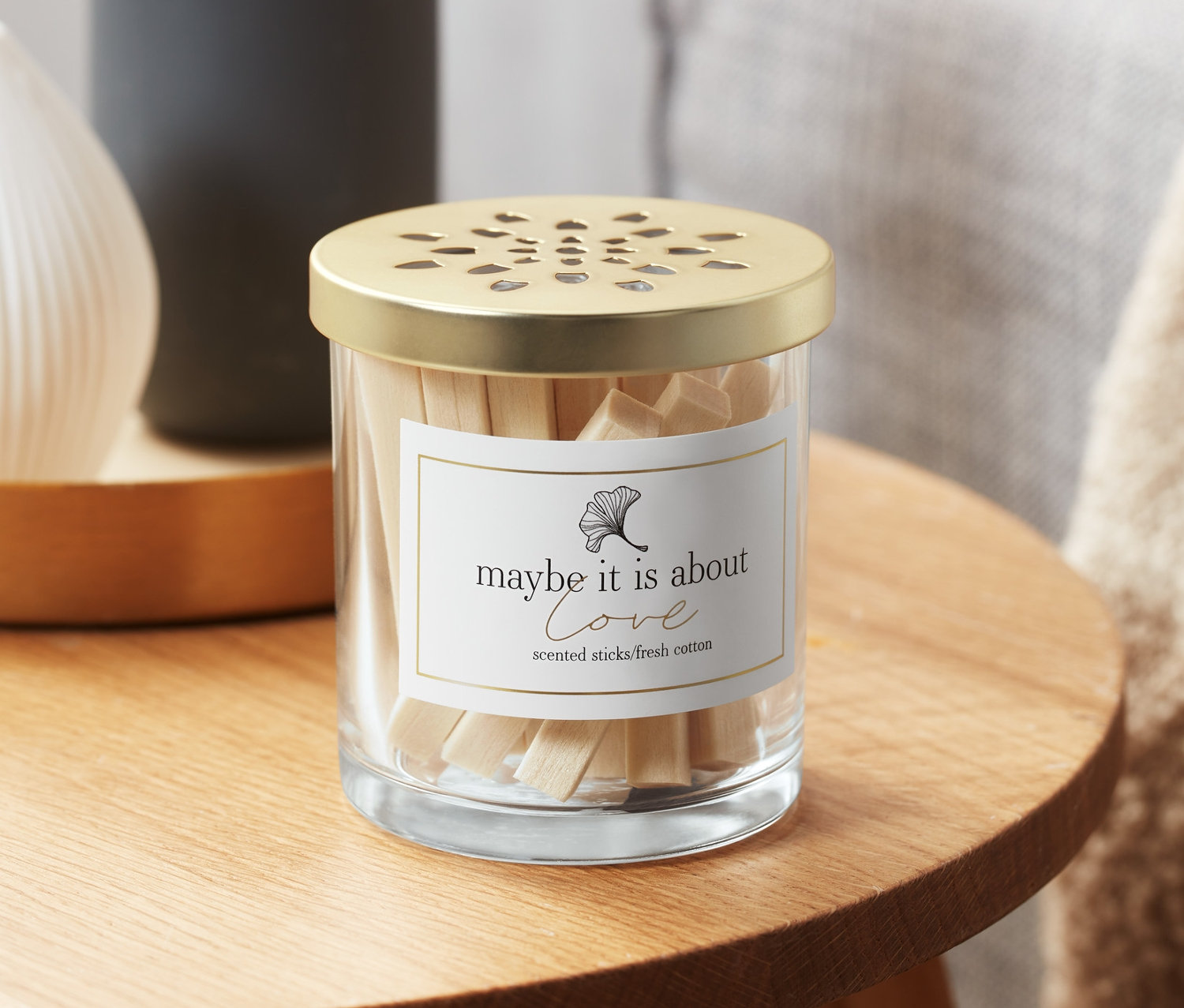 Sklenená nádoba s vonnými tyčinkami s vôňou bavlníkových polí na drevenom stolíku.