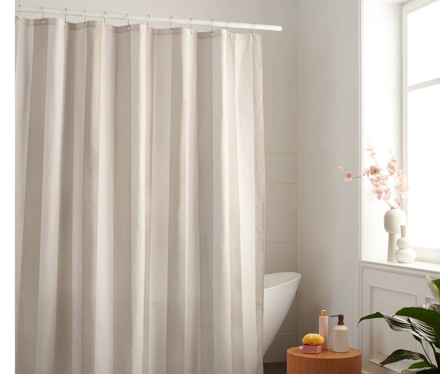 Béžovo-biely textilný sprchový záves visí v kúpeľni.