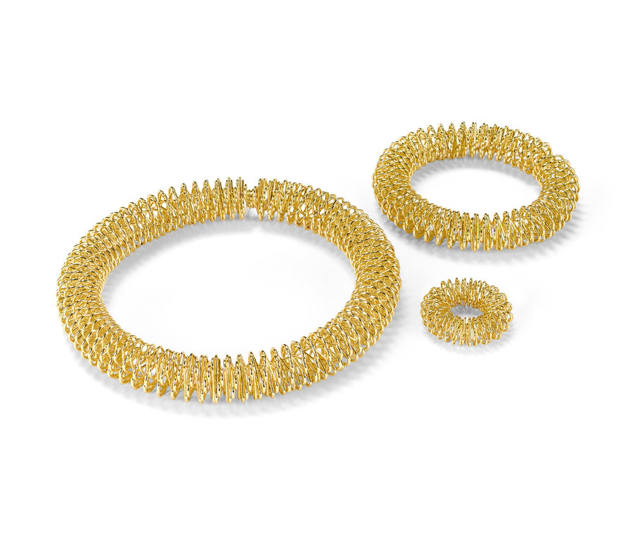 Zlatá akupresúrna súprava na bielom pozadí.