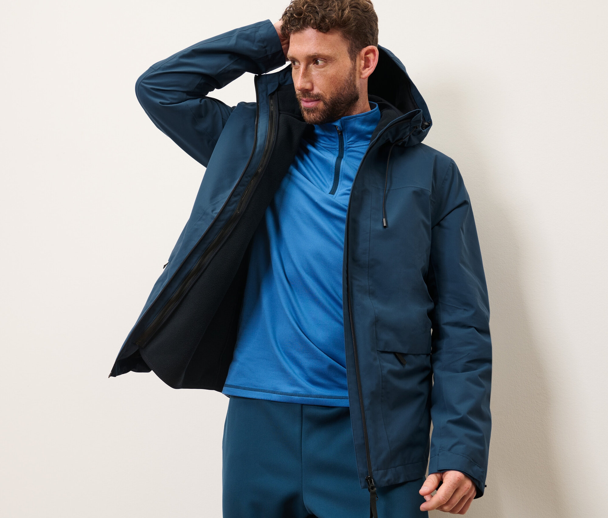 Muž pózuje v outdoorovej bunde s vestou.